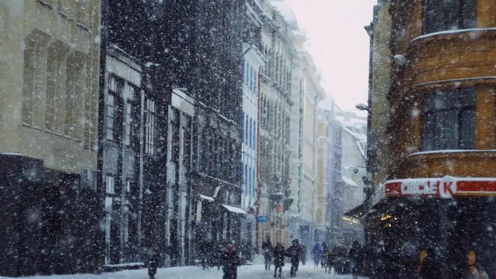 Cilvēki soļo pa sniegotu Rīgas ielu intensīvas snigšanas laikā ziemas periodā